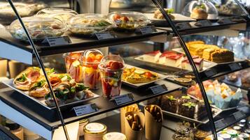 A variety of food items displayed in a glass case, including salads, sandwiches, and desserts.
