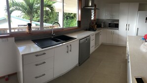 Una cocina moderna con armarios blancos, un lavamanos negro y un lavavajillas.
