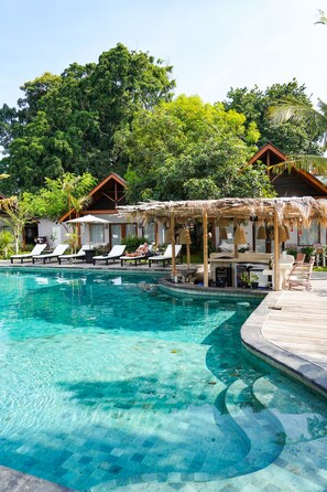 A clear swimming pool with lounge chairs and a wooden deck. - Kashantee Village (Keroboken Kelod)