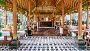 A traditional wooden pavilion with a tiled floor, seating areas, and a central fireplace.