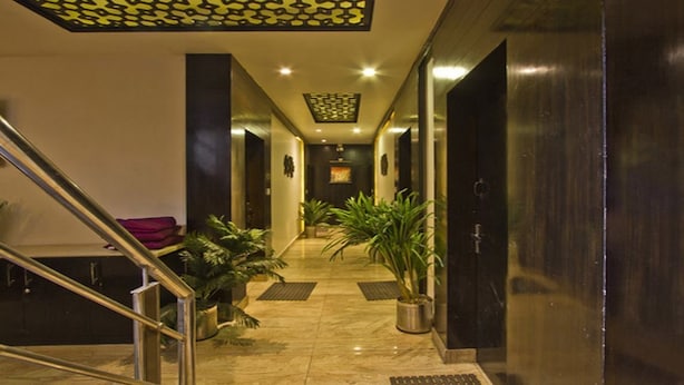 Rebedor d'hotel amb sòl de marbre, una escala i plantes en testos.