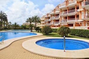 A hotel with multiple balconies, a swimming pool, and well-maintained landscaping.