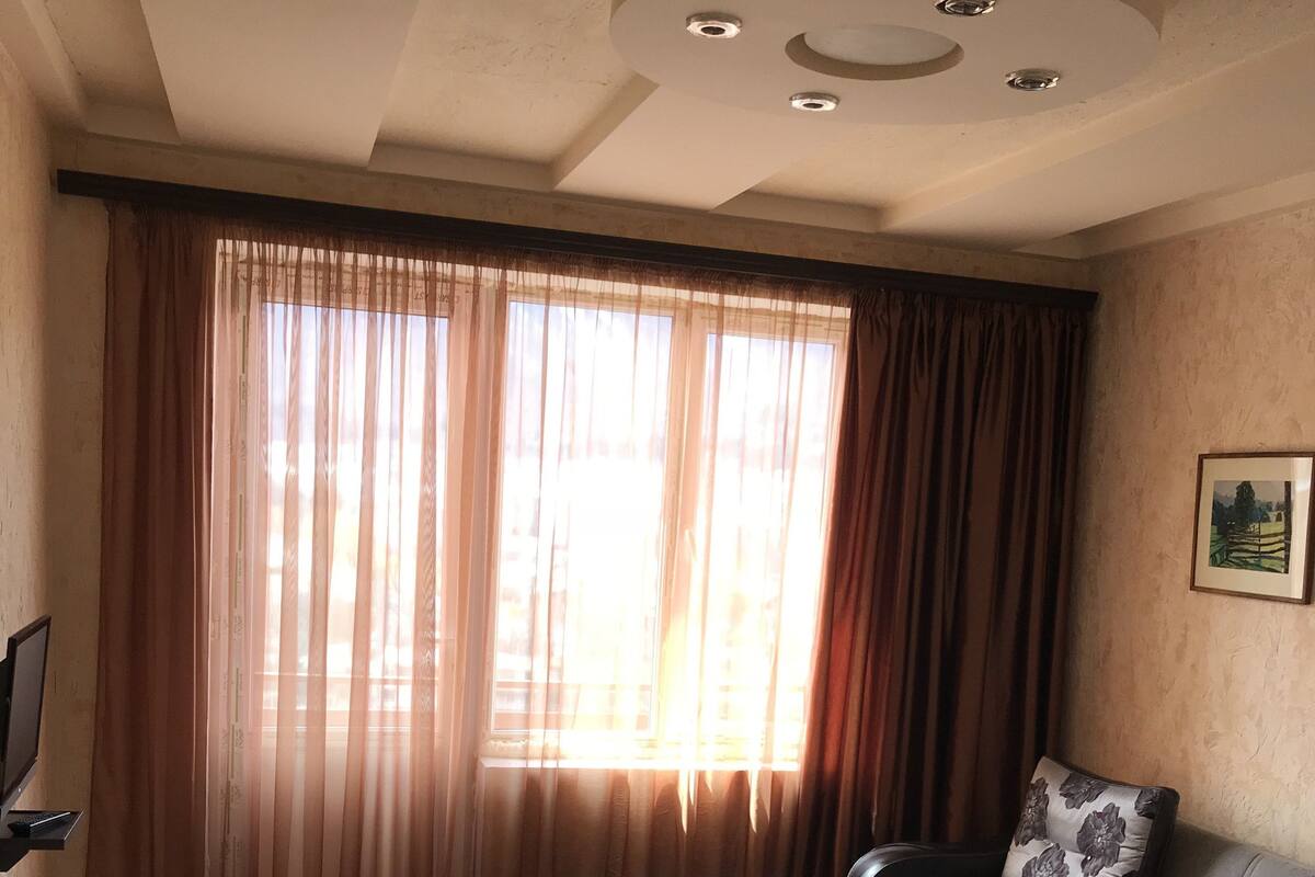 Quarto de hotel com uma cama, um sofá, uma mesinha e uma televisão.