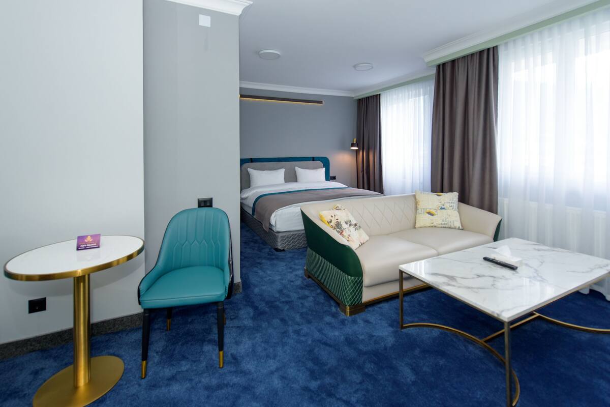 Quarto de hotel com uma cama, um sofá, uma mesa redonda pequena e uma cadeira.