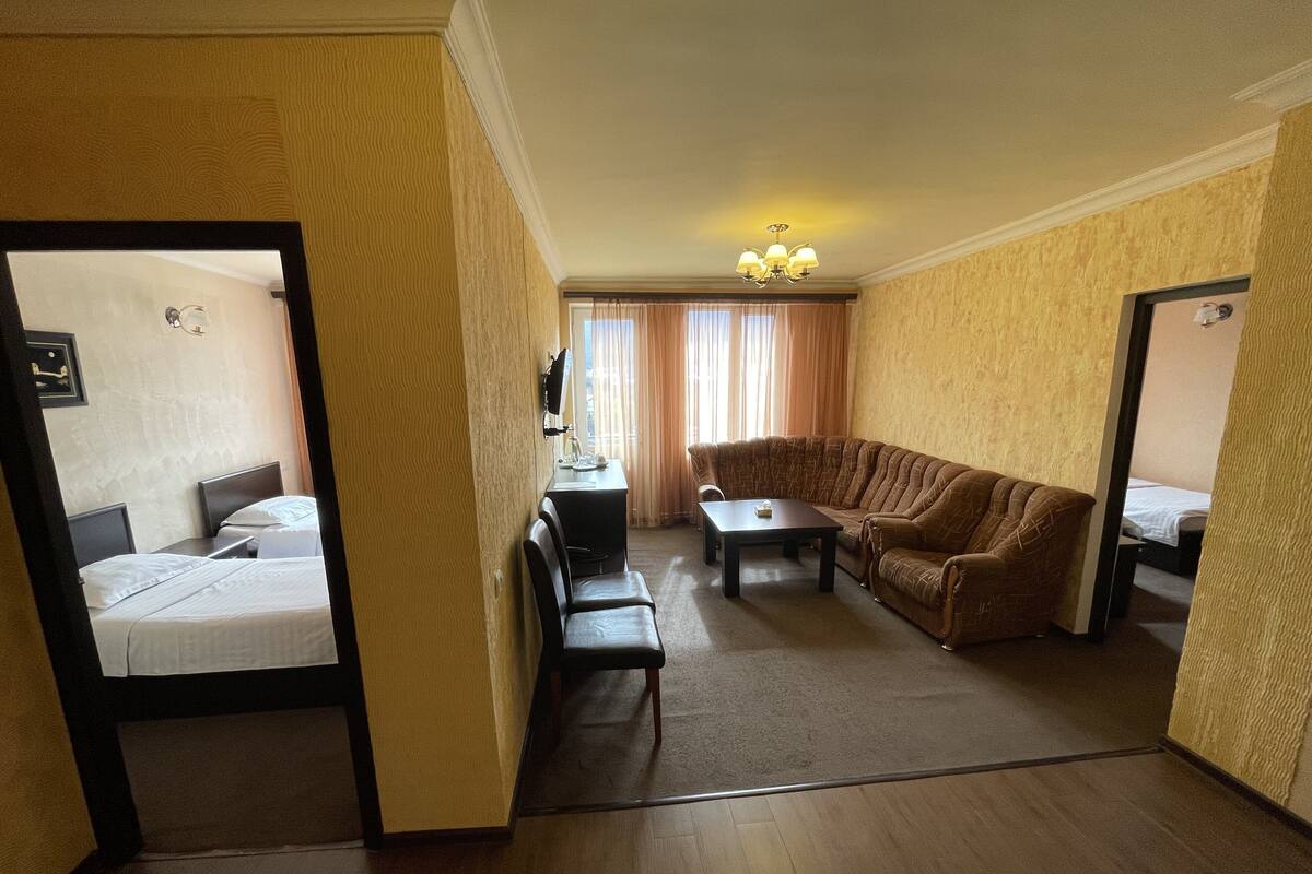 Quarto de hotel com cama, sofá, mesinha e escrivaninha com cadeira.