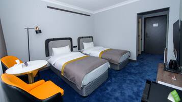 A hotel room with two beds, a desk, a chair, and a TV.