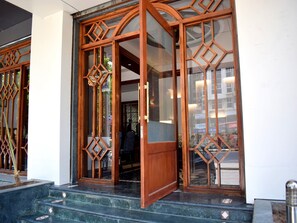 A building entrance with a wooden door and glass panels, featuring geometric patterns. - SRTC Hotel Aspire (Ahmedabad)
