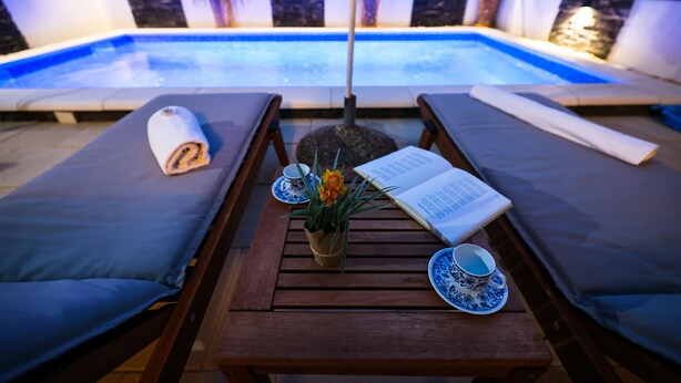 A poolside lounge area with two sunbeds, a table with a book, a vase with flowers, and a cup and saucer. - Apartment Rustica Zadar with exclusive use of pool & yard (Zadar)