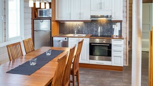 Une cuisine moderne avec des meubles blancs, des appareils en acier inoxydable et une table à manger en bois.