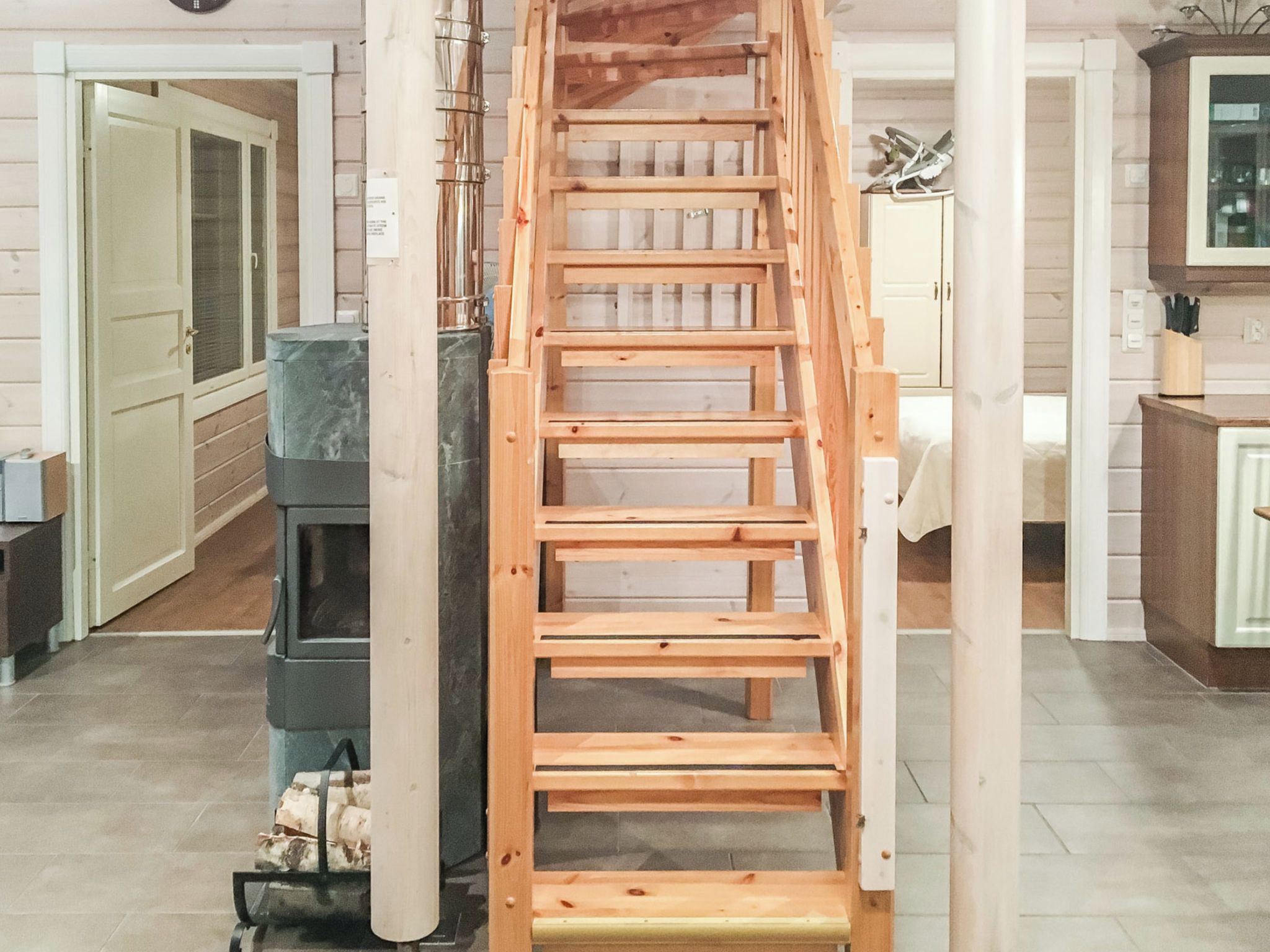 A wooden staircase leading to an upper floor, with a kitchen area visible below.