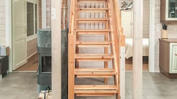 A wooden staircase leading to an upper floor, with a kitchen area visible below.