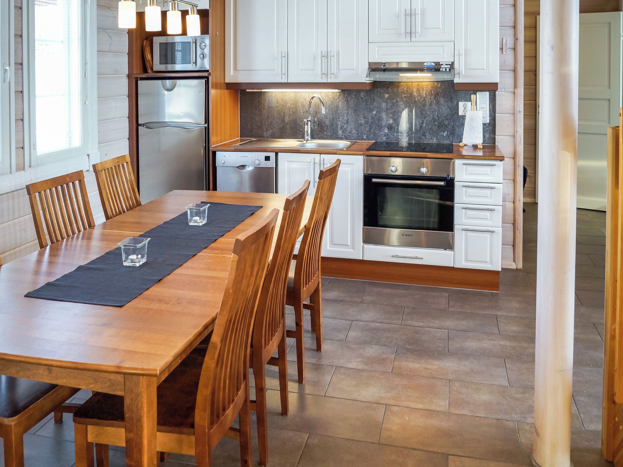 A modern kitchen with white cabinets, stainless steel appliances, and a wooden dining table with chairs.