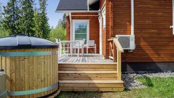 A wooden deck with outdoor furniture, a hot tub, and an air conditioning unit.