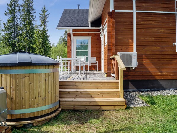 A wooden deck with outdoor furniture, a hot tub, and an air conditioning unit.