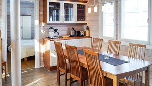 Une cuisine moderne avec des meubles blancs, une table à manger entourée de six chaises en bois et un bar pour prendre le petit-déjeuner.