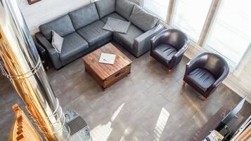 A modern living room with a sectional sofa, a wooden coffee table, and leather armchairs.