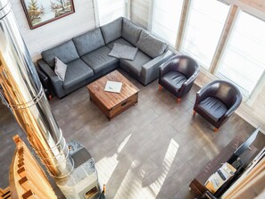 En moderne stue med en hjørnesofa, et træbord og læderlænestole.