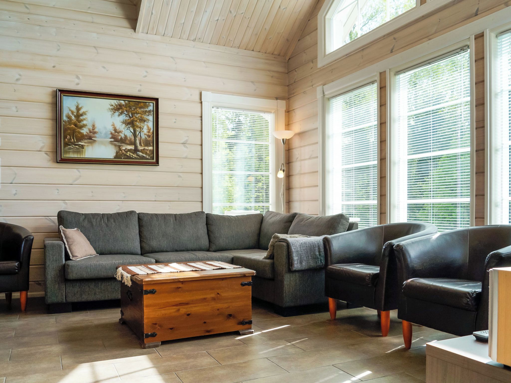 A cozy living room with a sectional sofa, a wooden coffee table, and a painting on the wall.