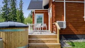 Une cabane en bois dotée d’une terrasse, d’un bain à remous et d’un espace extérieur aménagé et abrité.