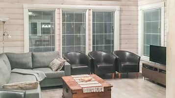 A living room with a sofa, two armchairs, a coffee table, and a television.
