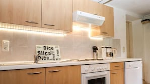 Moderni keittiö, jossa on puukalusteet, sisäänrakennettu uuni, astianpesukone ja kahvinkeitin työtasolla.