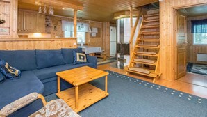 A wooden interior with a sofa, a small wooden table, and a wooden staircase. - Joutsen by Interhome (Kouvola)