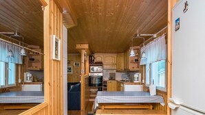 A compact kitchen with wooden cabinets, a microwave, and a sink. There are two wooden benches with checkered tablecloths. - Joutsen by Interhome (Kouvola)