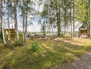 Un terrain de camping avec une cabane en bois, un petit abri et un bateau.
