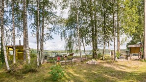 A rustic cabin with a wooden deck, surrounded by birch trees and a lake view. - Joutsen by Interhome (Kouvola)