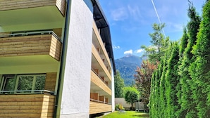 Un edificio moderno con facciata in legno, un balcone e vista sulle montagne.