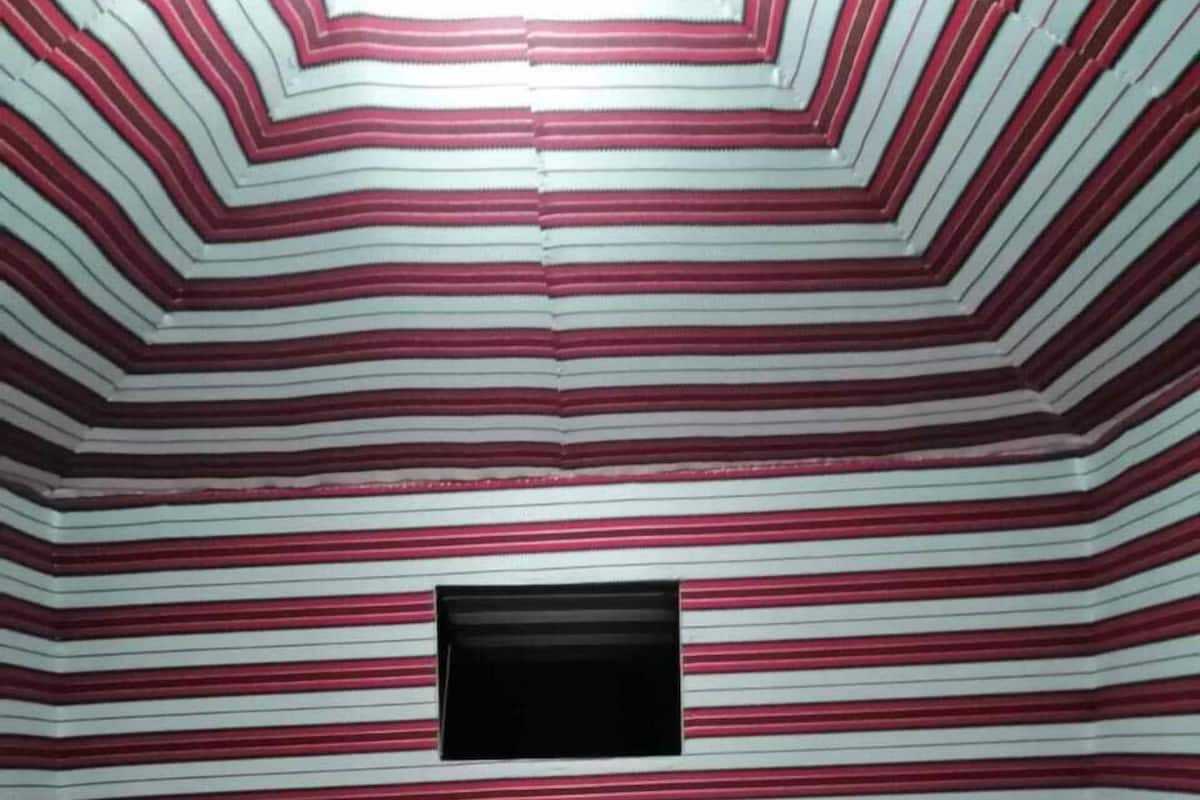 Une chambre avec deux lits, une petite fenêtre et un plancher en bois.