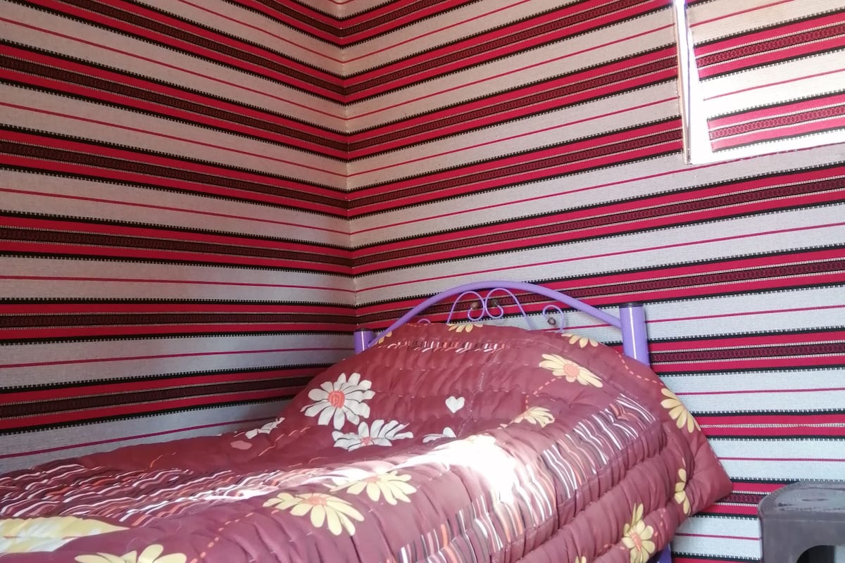 Une pièce avec un lit, une chaise et un motif à rayures sur le mur.
