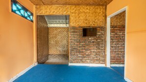 A hallway with a blue carpet, wooden ceiling, and brick walls. - OYO 644 Grand Yustik Selabintana (Sukabumi)