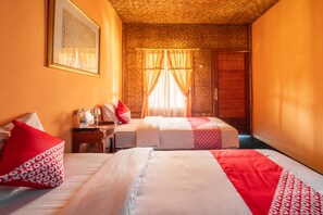 A room with two beds, each with white and red bedding, a wooden headboard, a small table with a lamp, and a framed picture on the wall. - OYO 644 Grand Yustik Selabintana (Sukabumi)