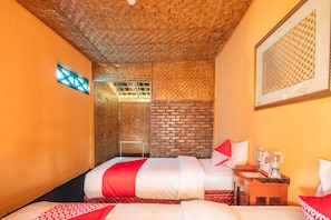 Habitación de hotel con dos camas, pared de ladrillo, techo de madera y una mesita con artículos de aseo.