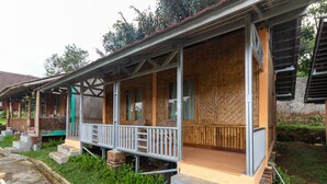 A wooden house with a porch, steps, and a garden. - OYO 644 Grand Yustik Selabintana (Sukabumi)