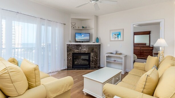 A living room with a fireplace, a television, and a ceiling fan. - Beautiful 3 bedroom condo, mid town, ocean block (Ocean City)