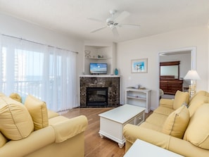 A living room with a fireplace, a television, and a ceiling fan. - Beautiful 3 bedroom condo, mid town, ocean block (Ocean City)