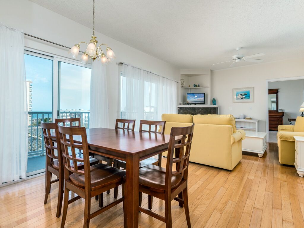 A spacious living area with a wooden dining table, yellow sofa, and a television.
