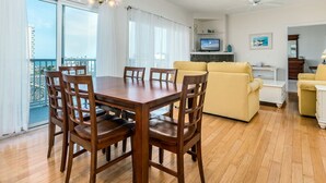 A spacious living area with a wooden dining table, yellow sofa, and a television. - Beautiful 3 bedroom condo, mid town, ocean block (Ocean City)