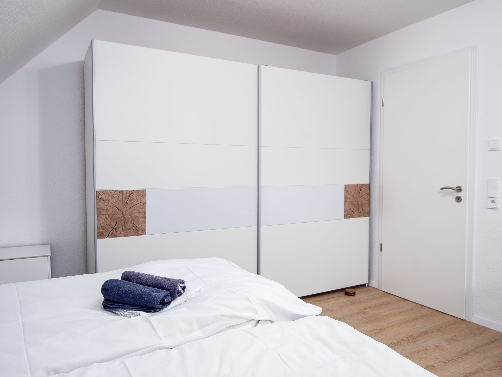 Une chambre à coucher avec un lit, une armoire blanche et une porte.