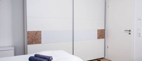 Une chambre à coucher avec un lit, une armoire blanche et une porte.