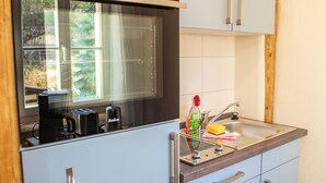 Eine kleine Küche mit integriertem Backofen, einer Kaffeemaschine und einem Spülbecken.
