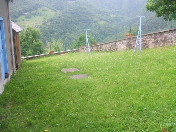 Une zone herbeuse avec un mur de pierre et un bâtiment bleu.
