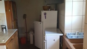 Une cuisine de taille réduite, équipée d’un réfrigérateur, d’un évier et de meubles de rangement en bois.