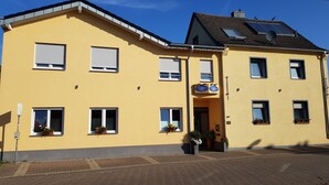 A yellow building with multiple windows, a door, and a sign indicating it is a hotel. - Hotel Landhaus Effeld (Wassenberg)