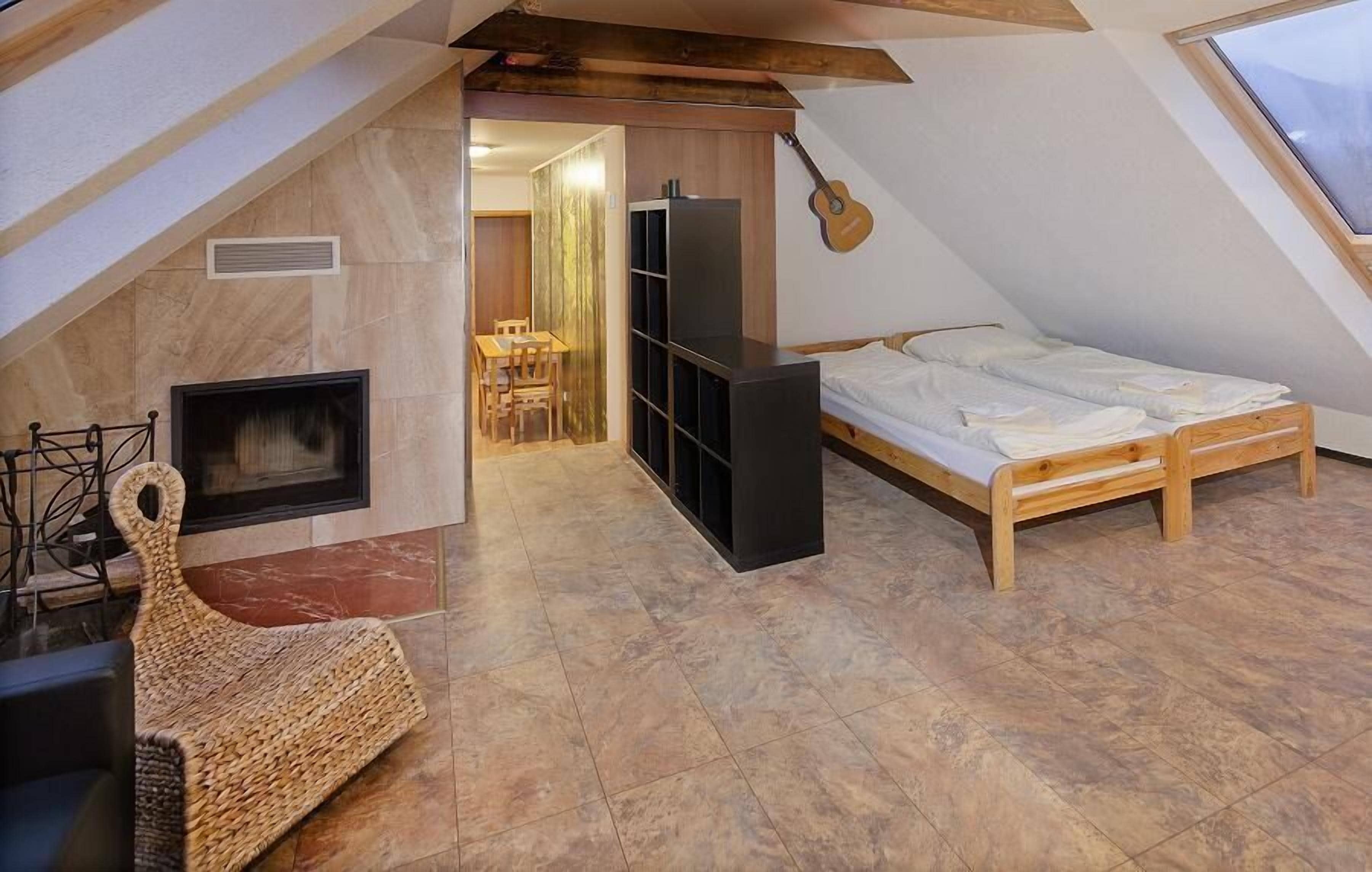 Un acogedor dormitorio en el ático con chimenea, una cama y una guitarra en la pared.