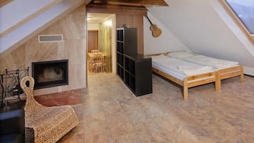 Un acogedor dormitorio en el ático con chimenea, una cama y una guitarra en la pared.
