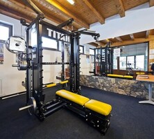 A gym with weightlifting equipment, a bench, and a stone wall.