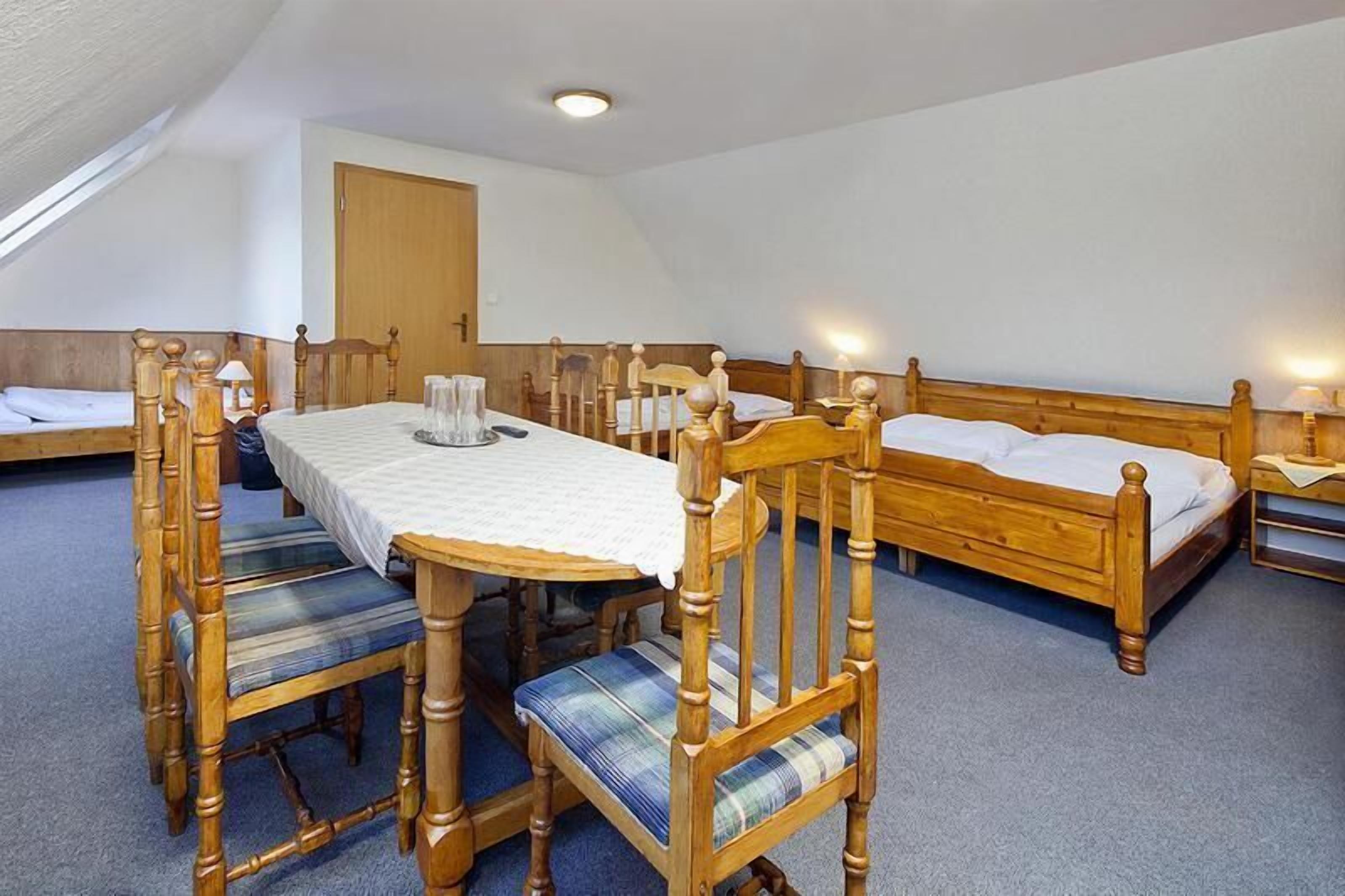 Una habitación con una mesa de comedor de madera, sillas y una cama con cabeceros de madera.